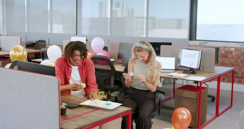 Colleagues celebrating birthday in modern office with decorations