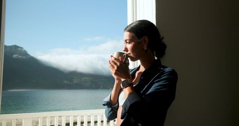 Woman Sipping Coffee on Balcony with Scenic Mountain View