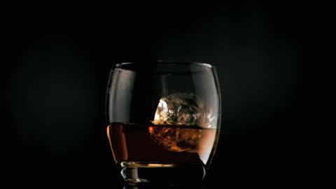 Slow Motion Ice Cube Drop into Whiskey Glass
