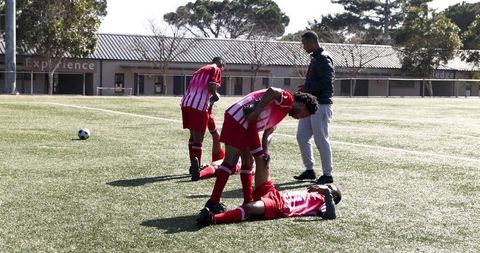 Soccer teammates assisting injured player on field during training