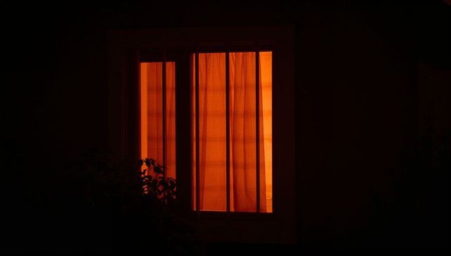Warm, glowing window with silhouetted nighttime ambiance