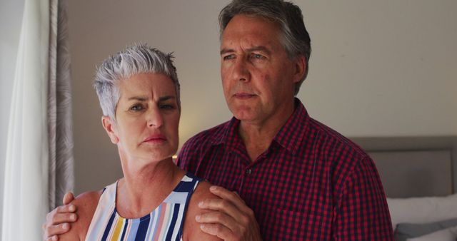 Stressed caucasian senior couple talking to each other while looking out of the window at home. retirement senior couple lifestyle living concept