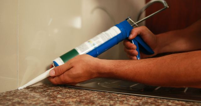 Close-up of Man Using Caulking Gun for Kitchen Renovation - Download Free Stock Images Pikwizard.com