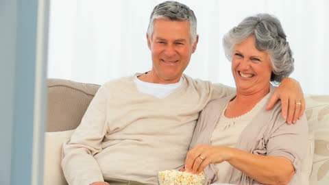 Happy Senior Couple Relaxing With Popcorn on Couch