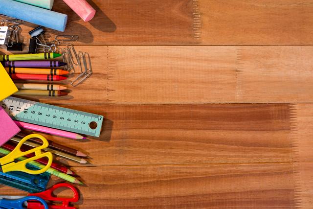 This image captures a variety of colorful stationery items spread across a wooden table, perfect for themes related to school, education, and creativity. Ideal for advertisements, blogs, or social media posts about back-to-school season, office supplies, and art projects.