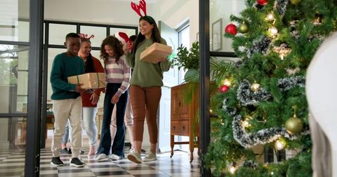 Smiling Family Entering Home Holding Christmas Gifts