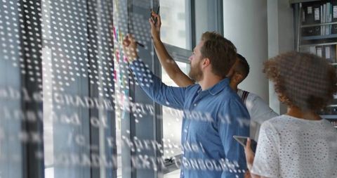 Creative Team Brainstorming on Glass Whiteboard in Modern Office