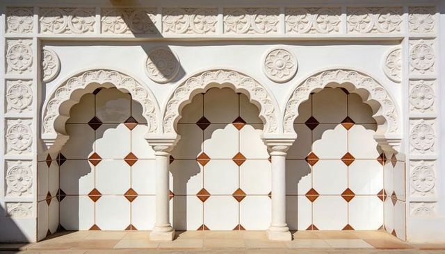Sunlit moorish scalloped arches with ornate columns and geometric decorative tile alcoves