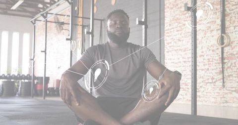 Bearded man meditating on gym mat, sitting cross-legged in minimalist light-filled gym