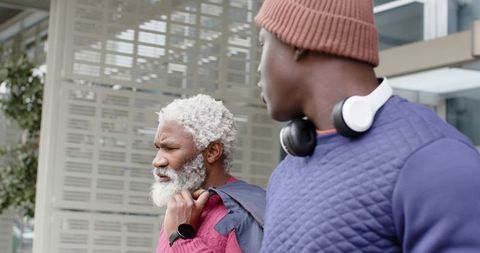 African american men walking city sidewalk wearing knit sweaters, beanie and headphones