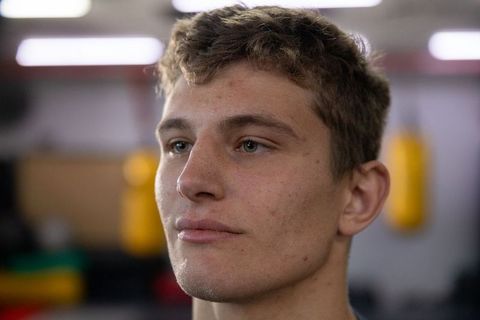 Young male athlete looking upward in gym with punching bags close-up portrait contemplating