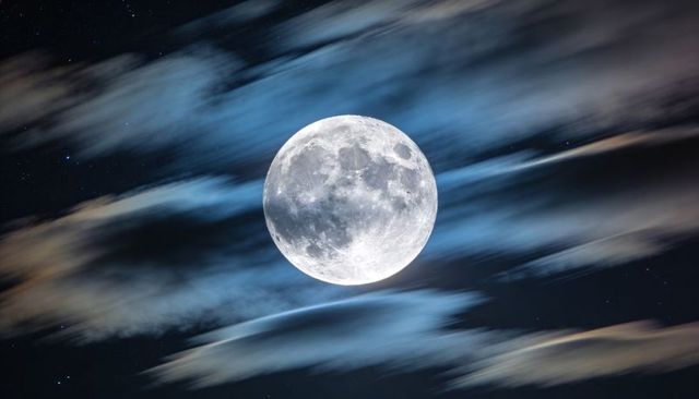 Full Moon Illuminating Cloud Streaks Over Night Sky Showing Craters and Maria