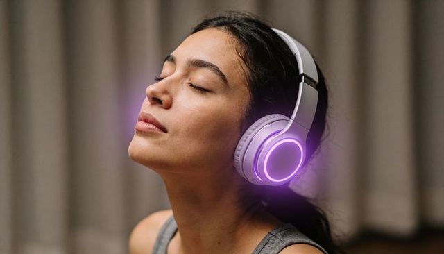 Young woman relaxing with glowing wireless headphones enjoying music and calm expression