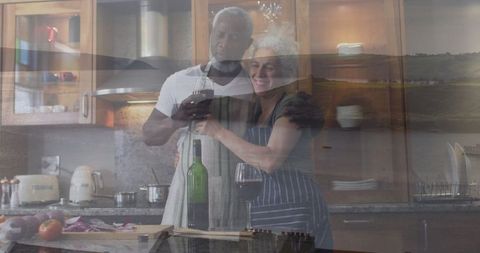 Romantic couple cooking and toasting wine in kitchen