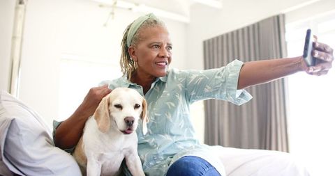 Senior Woman with Dog Taking Selfie on Bed at Home