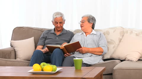 Senior Couple Relaxing on Sofa Reviewing Photo Album