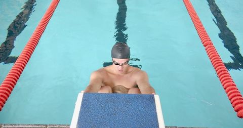 Competitive Male Swimmer Preparing for Race in Lane