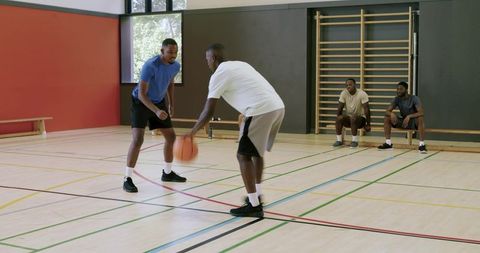 African american athletes performing crossover dribble while defender guarding in court