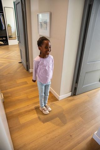 Smiling african american girl standing in modern hallway wearing casual top and sneakers