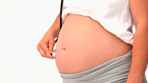 Pregnant Woman Using Stethoscope on Belly to Listen to Baby