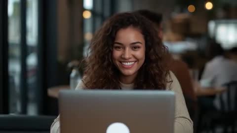 Woman Smiling While Engaging with Laptop in Cozy Cafe Setting