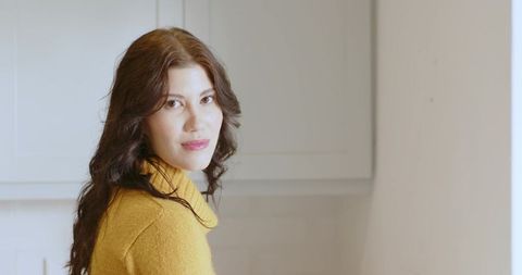 Woman in home kitchen looking over shoulder