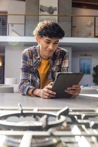 Young man using tablet in modern kitchen interior