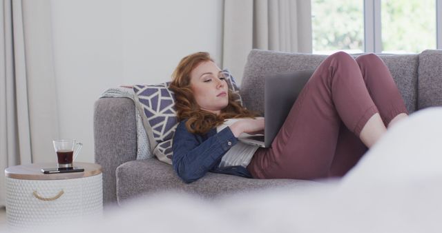 Young woman freelancing on laptop while relaxing on sofa - Download Free Stock Images Pikwizard.com