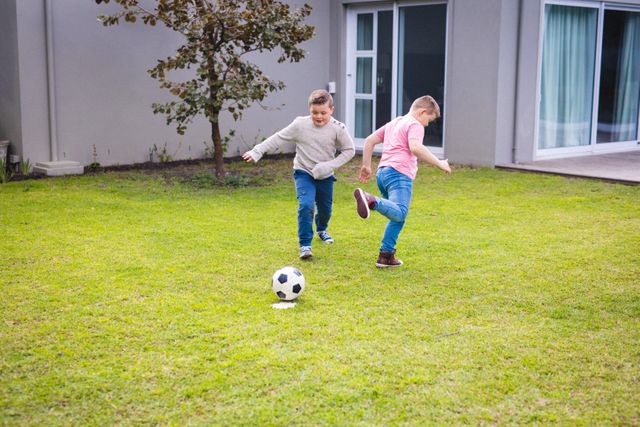 Two caucasian boys playing football together in the garden outdoors. childhood, hobby and sports concept