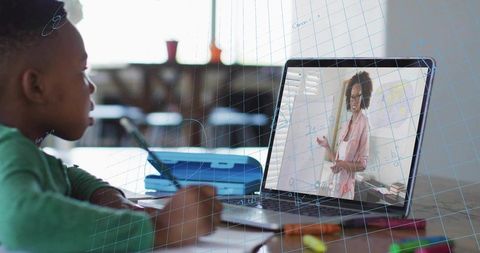 Young boy studying math during remote laptop lesson at home, watching teacher on screen