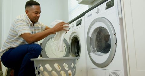 Man loading washing machine laundry homemaking routine