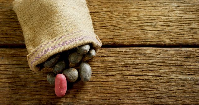 A burlap sack spills an assortment of colorful beans onto a rustic wooden surface, with copy space. Beans are a staple food in many cultures, valued for their nutritional benefits and versatility in cooking.