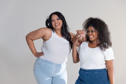 Smiling diverse plus-size friends posing confidently in white tops and blue denim