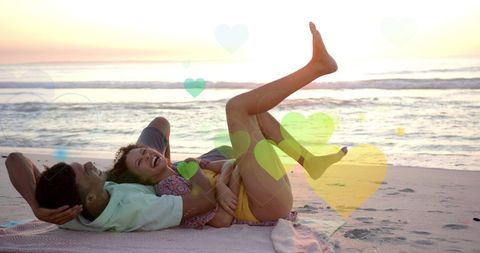 Romantic Couple Relaxing on Sunny Beach with Heart Overlays