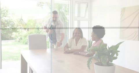 Pouring coffee for multigenerational family around wooden table with garden view and sunlight