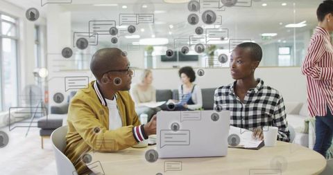 Mid-career professionals collaborating in modern coworking lounge pointing at laptop