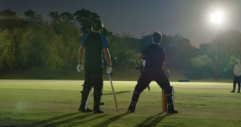 Night cricket under floodlights batsmen preparing at crease wicketkeeper appealing