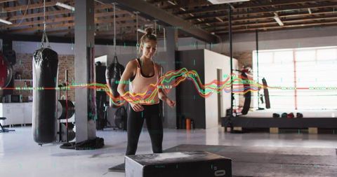 Female athlete preparing for plyo box jump in industrial gym with performance data overlay