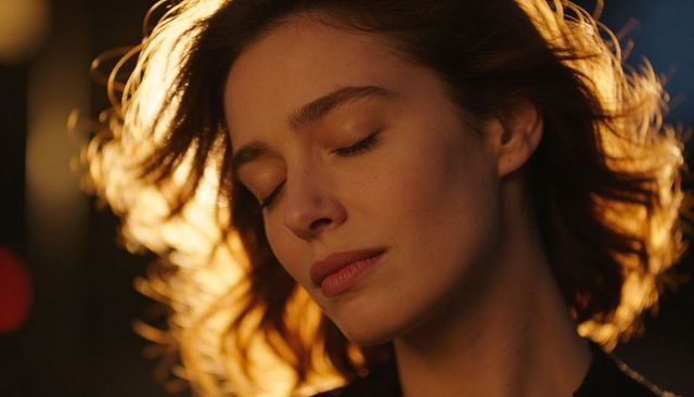 Serene woman eyes closed in golden backlight, closeup portrait with warm rim halo