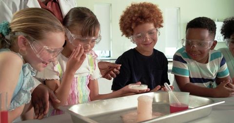 Elementary students conducting baking soda volcano experiment with teacher in science class