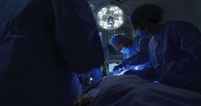 Surgeons are performing a delicate operation on a patient in a dimly-lit operating room. The medical team is focused and coordinated, illuminated by surgical lights, highlighting the critical nature of their work. This image can be used in medical articles, healthcare websites, or educational materials regarding surgery and healthcare.