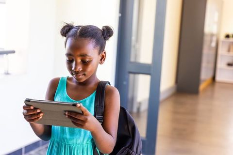 African american student using tablet in school hallway for digital learning and focus