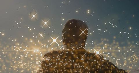 Backlit mature male silhouette at dusk with golden bokeh and star flares