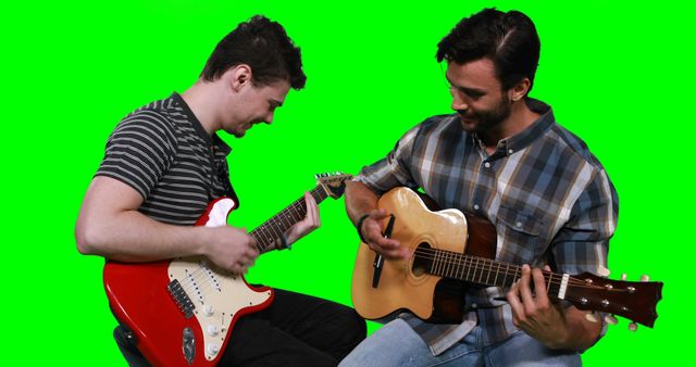 Two men sitting and playing guitars, one with an electric guitar and the other with an acoustic guitar, against a green background. Suitable for music lessons, band promotions, or collaborative artistic projects.