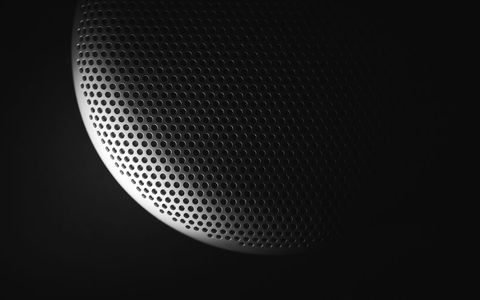 Featuring perforated metal speaker grille showcasing dramatic low-key lighting and texture