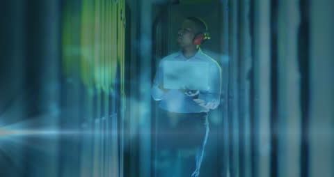 Young Professional Analyzing Data in Server Room with Headphones