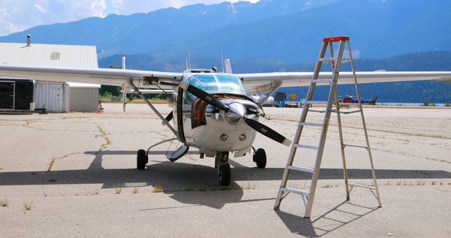 Small Airplane on Airfield with Ladder and Mountain Background - Download Free Stock Images Pikwizard.com