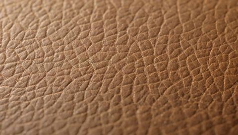 Brown pebble-grain leather texture featuring micro-creases, warm patina and tactile sheen