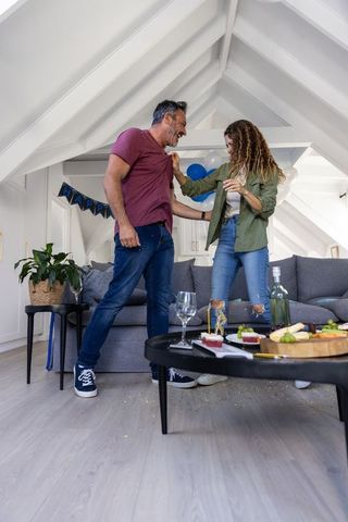 Couple celebrating with wine and charcuterie in cozy loft living room birthday party