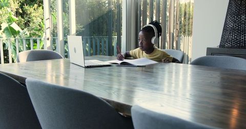 Young boy focused on remote learning at dining table